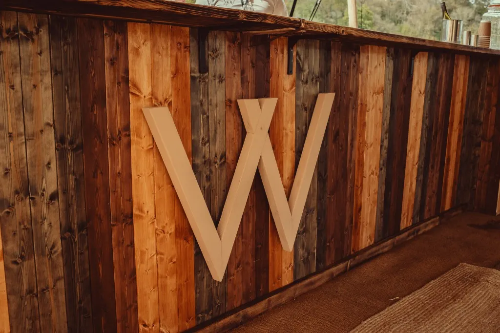 Rustic timber bar with the Woodhill W monogram at Woodhill Weddings, Faversham, Kent
