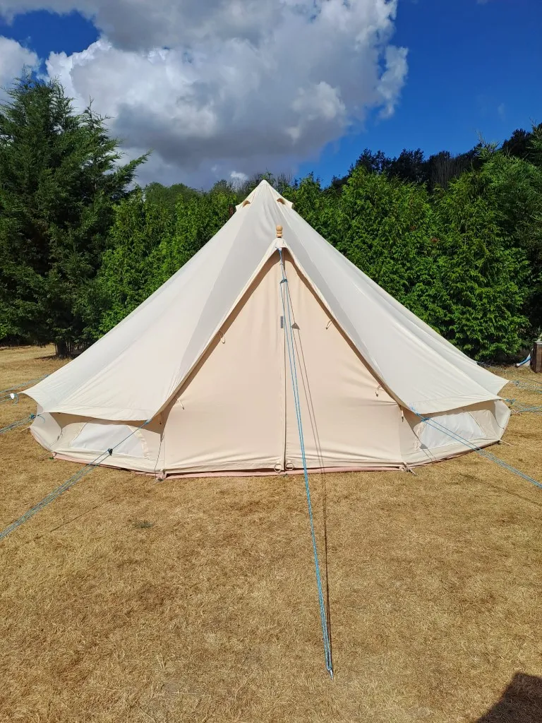 A cream canvas bell tent pitched in the grounds at Woodhill Campsite, Faversham, Kent