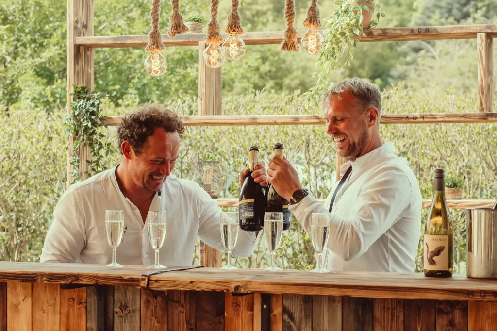 Guests toasting with champagne at the outdoor bar at Woodhill Weddings, Faversham, Kent