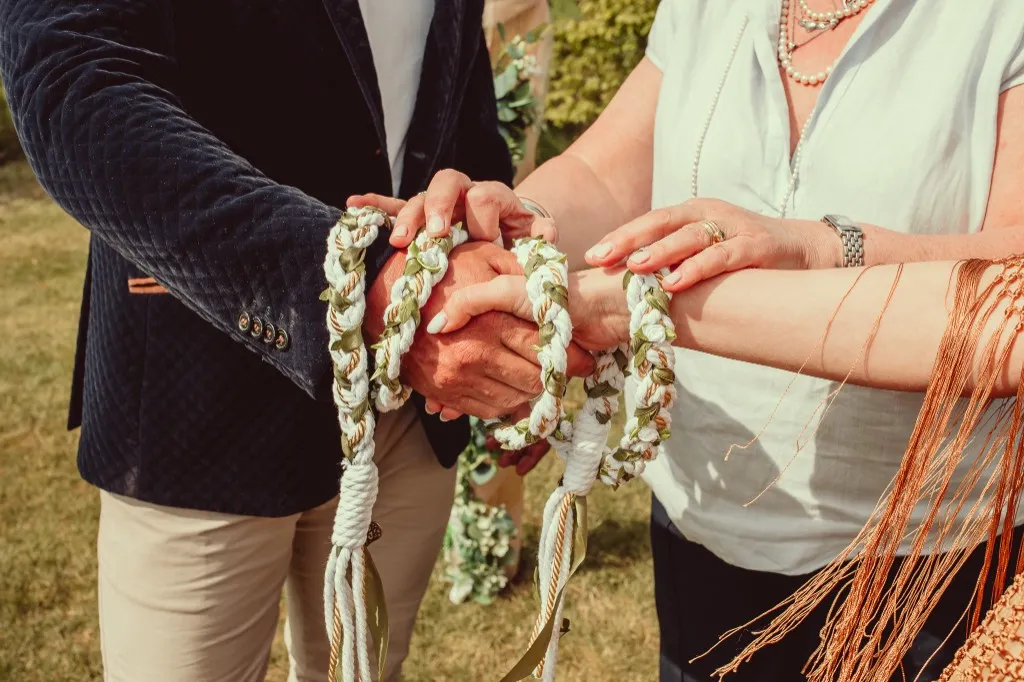 Handfasting cords tied around a couple's hands during a ceremony at Woodhill Weddings, Faversham, Kent