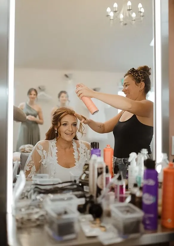 Karlie styling a bride’s hair on the morning of her wedding, with bridesmaids looking on