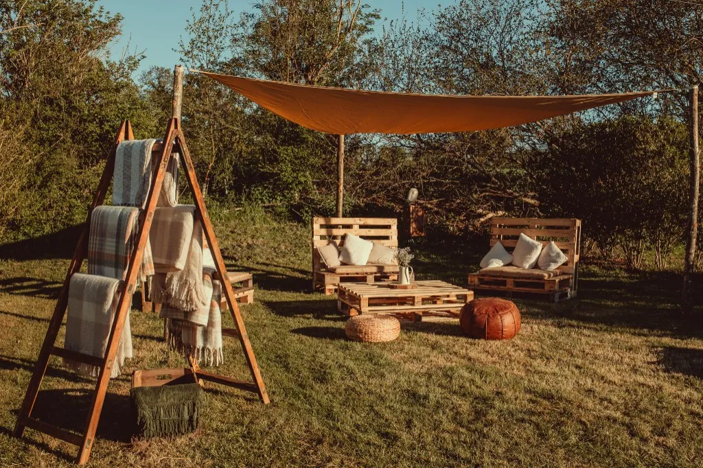 Outdoor pallet lounge seating with blankets under a sun sail at Woodhill Weddings, Faversham, Kent