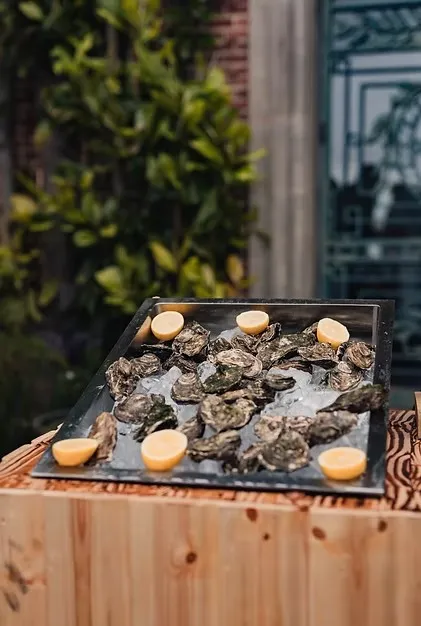 A tray of fresh oysters on ice with lemon halves from Oyster Buoys