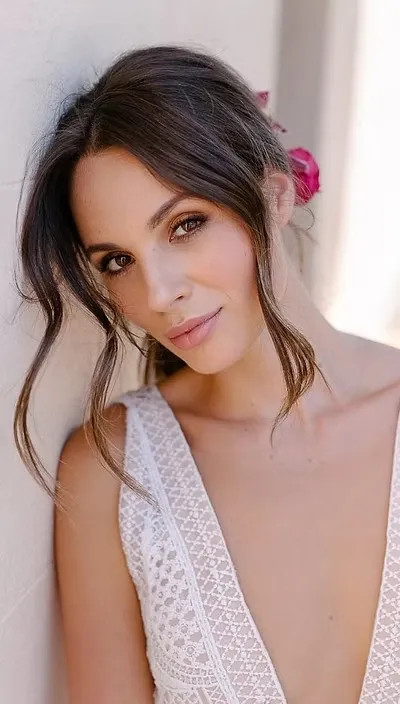 A bride with soft, romantic bridal makeup and a floral hairpiece by Rebecca Brown MUA