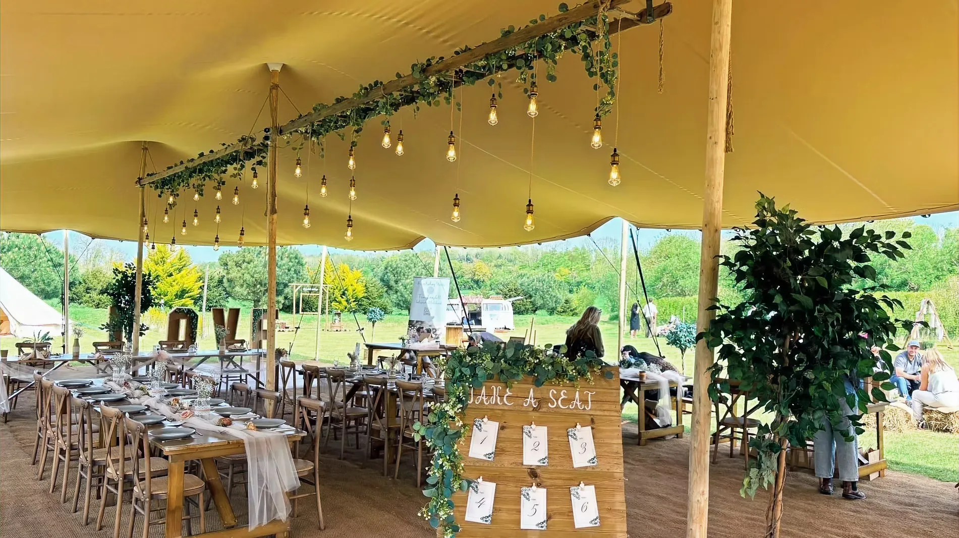 Guest tables dressed under the Bedouin stretch tent with a Take a Seat table plan at Woodhill Weddings, Faversham, Kent