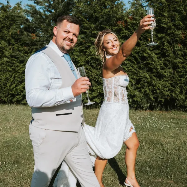 A bride and groom raising a champagne toast in the grounds at Woodhill Weddings, Faversham, Kent
