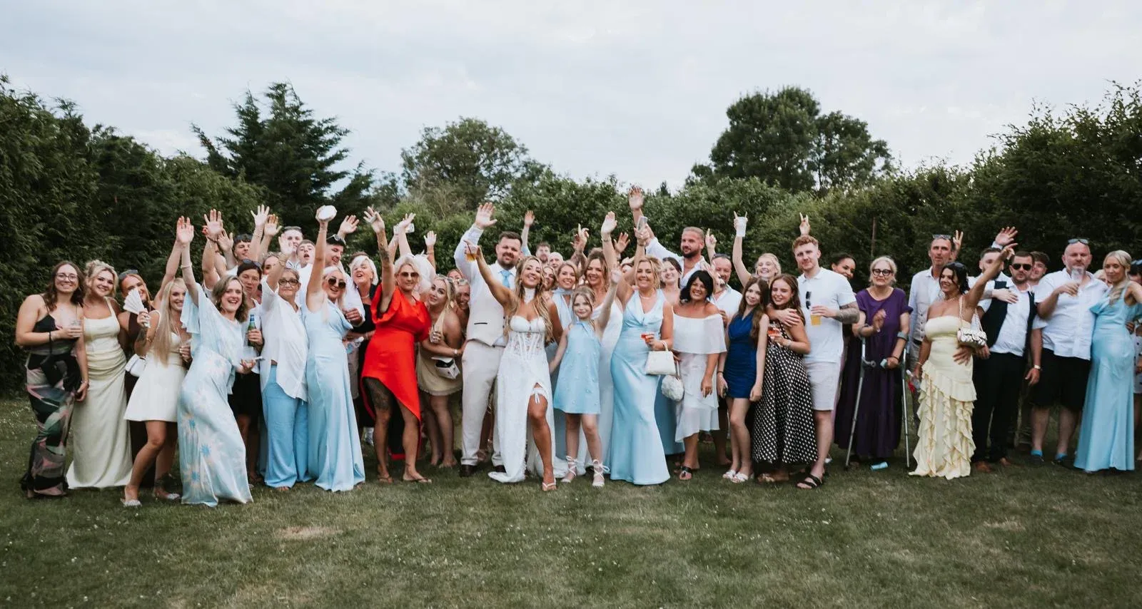 The wedding party and guests gathered for a group photo in the grounds at Woodhill Weddings, Faversham, Kent