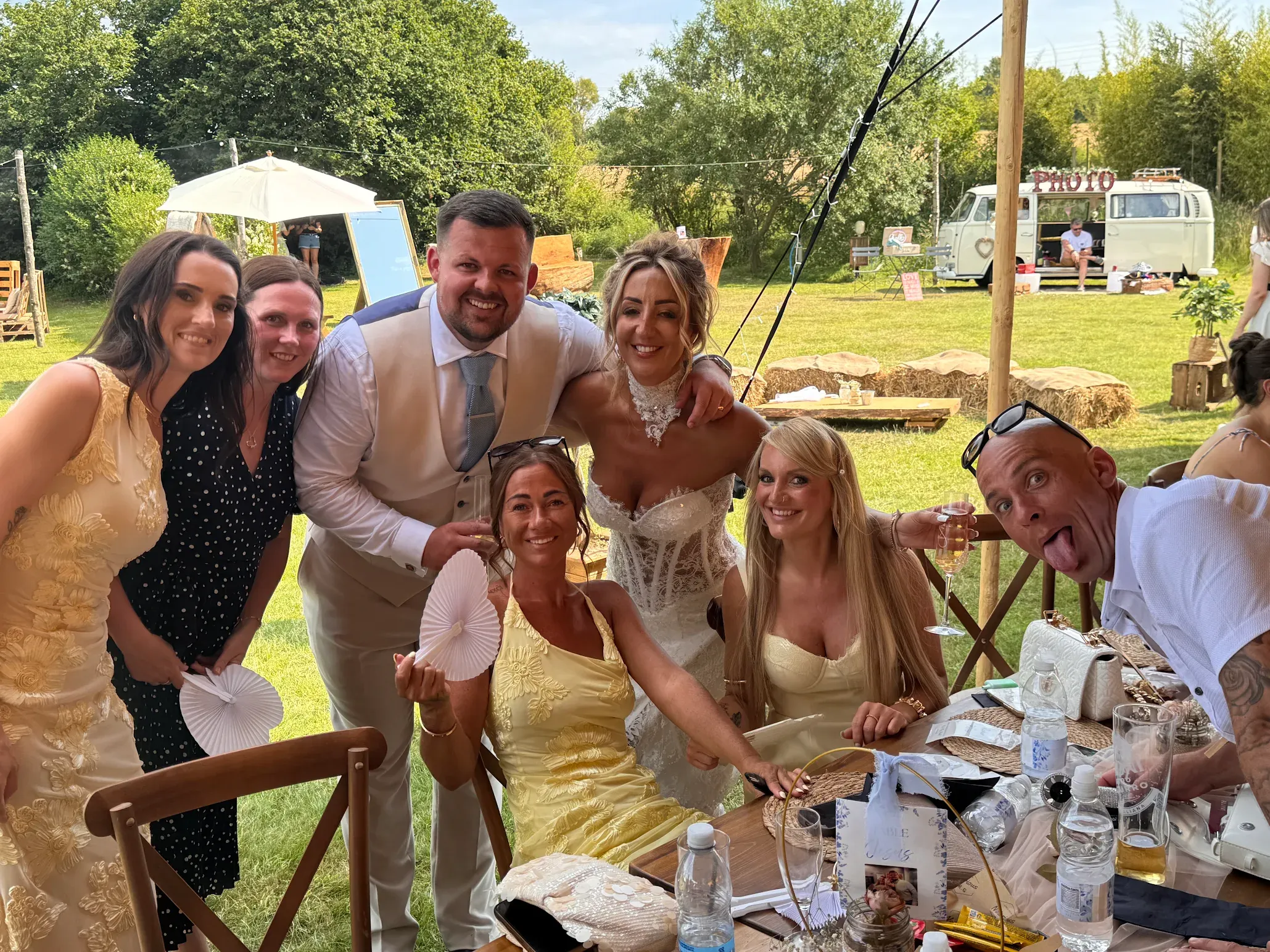 Wedding guests laughing together with the VW camper photo booth behind them at Woodhill Weddings, Faversham, Kent